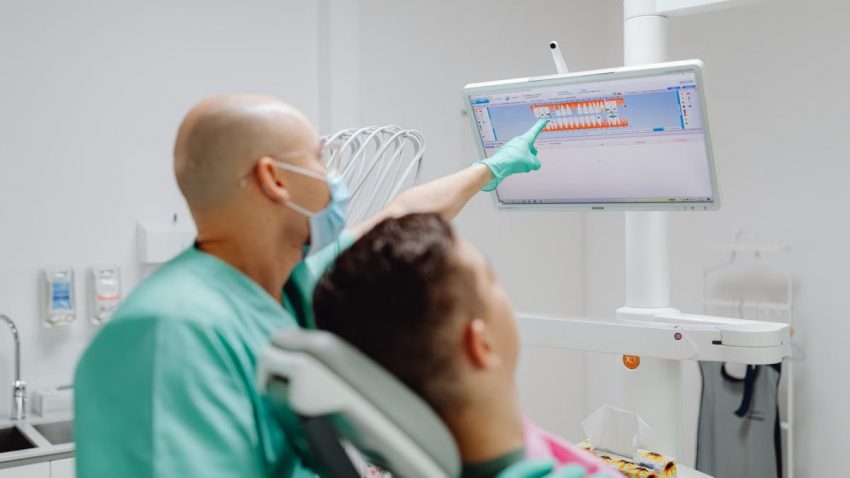Dentist examining patient with dental imaging software in modern clinic.